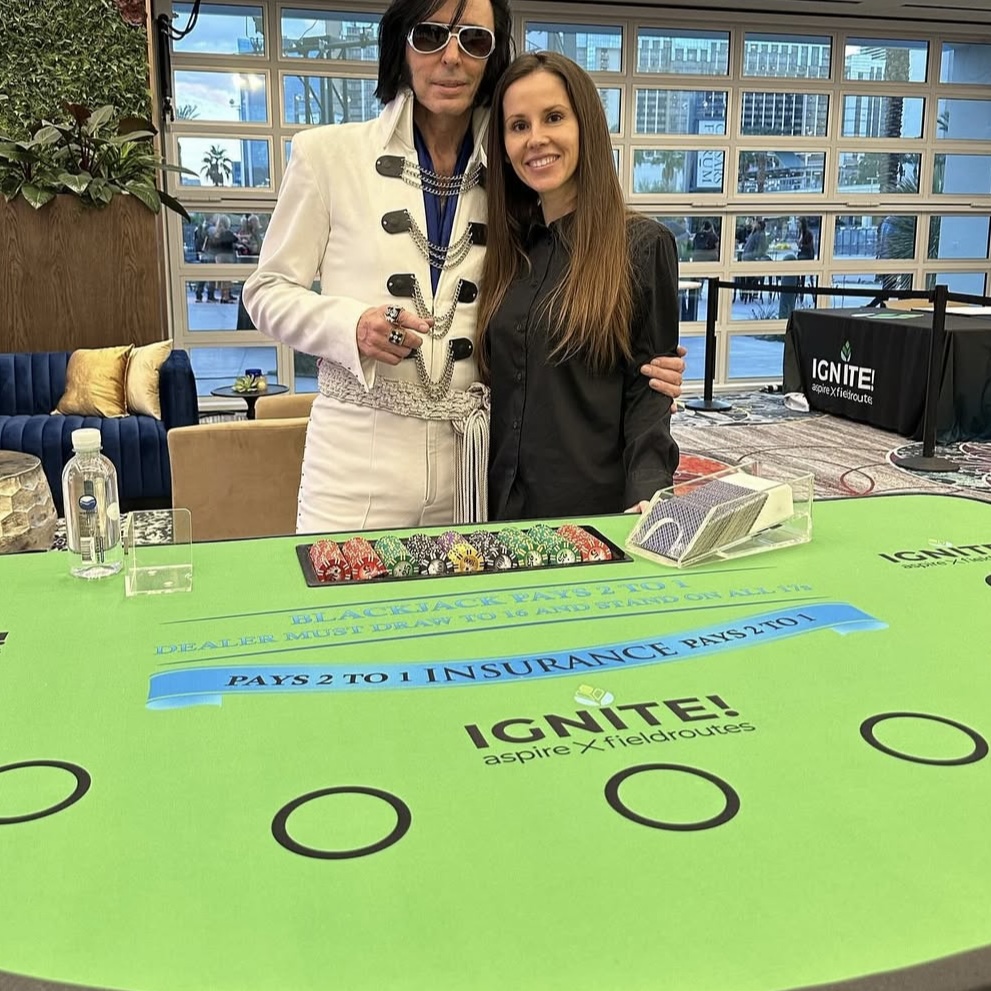 CPD dealer running a corporate casino night blackjack table with an Elvis impersonator guest